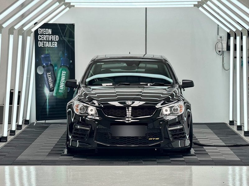 Black car front on inside a light tunnel at Elite Car Detailing Studio, on an ULTRAGRID floor in Jet Black and Space Grey with Jet Black ULTRAEDGE ramps