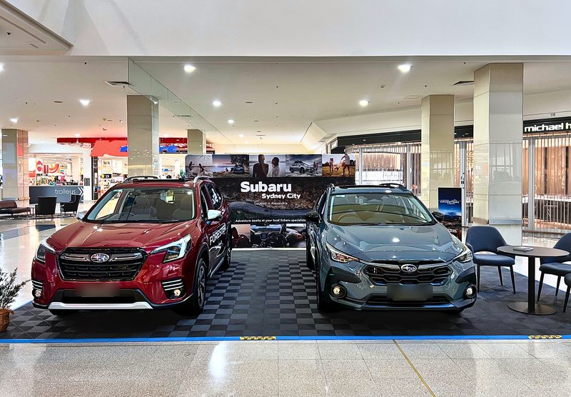 A red Subaru Forester and a grey Subaru Crosstrek on show in a shopping centre, on ULTRAGRID Space Grey tiles with ULTRAEDGE Riviera Blue ramps along the front