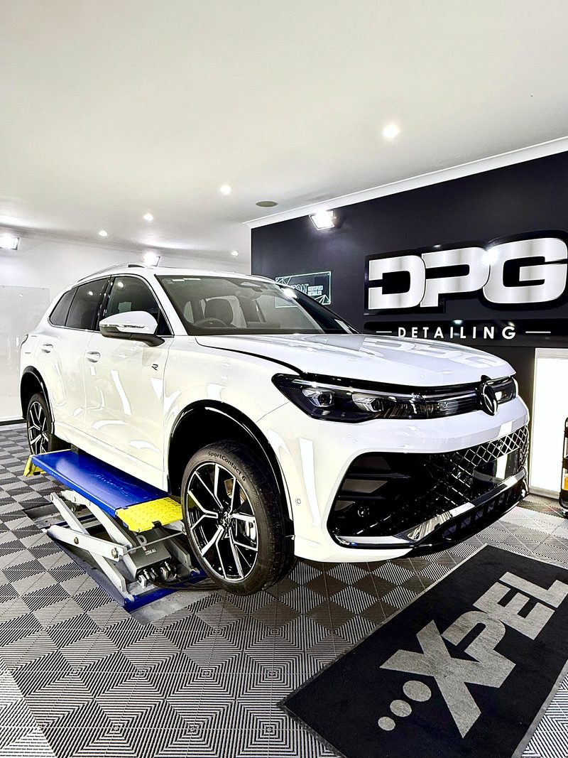 White SUV under the DPG Detailing wall sign, with the ULTRAGRID floor in Jet Black, Silver Grey and Space Grey below