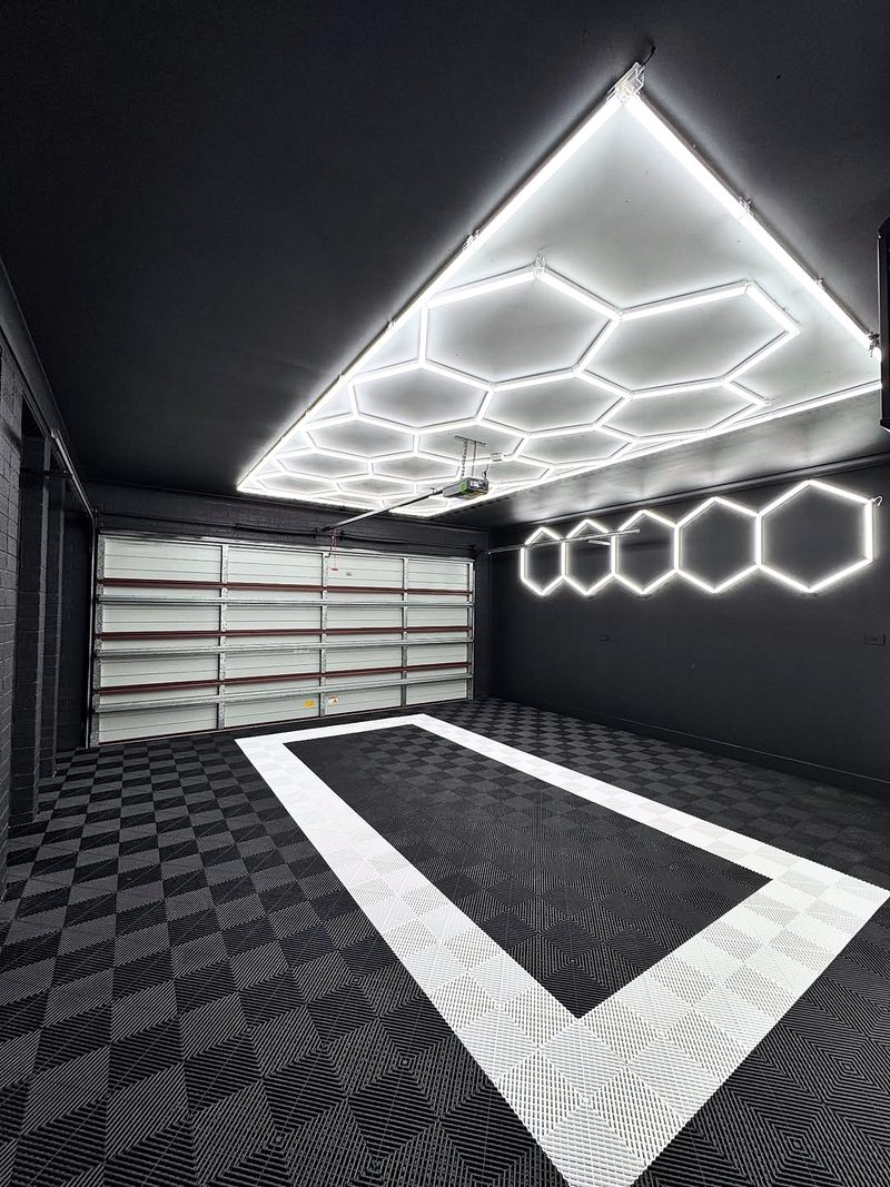A garage floor of ULTRAGRID Jet Black tiles with an Alpine White outline of a car bay, black walls