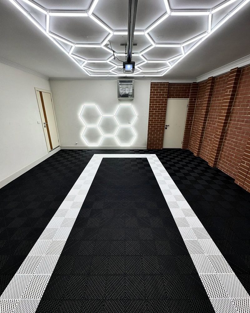 Looking down the garage: an Alpine White outline on the Jet Black ULTRAGRID chequer, brick wall on the right, white walls