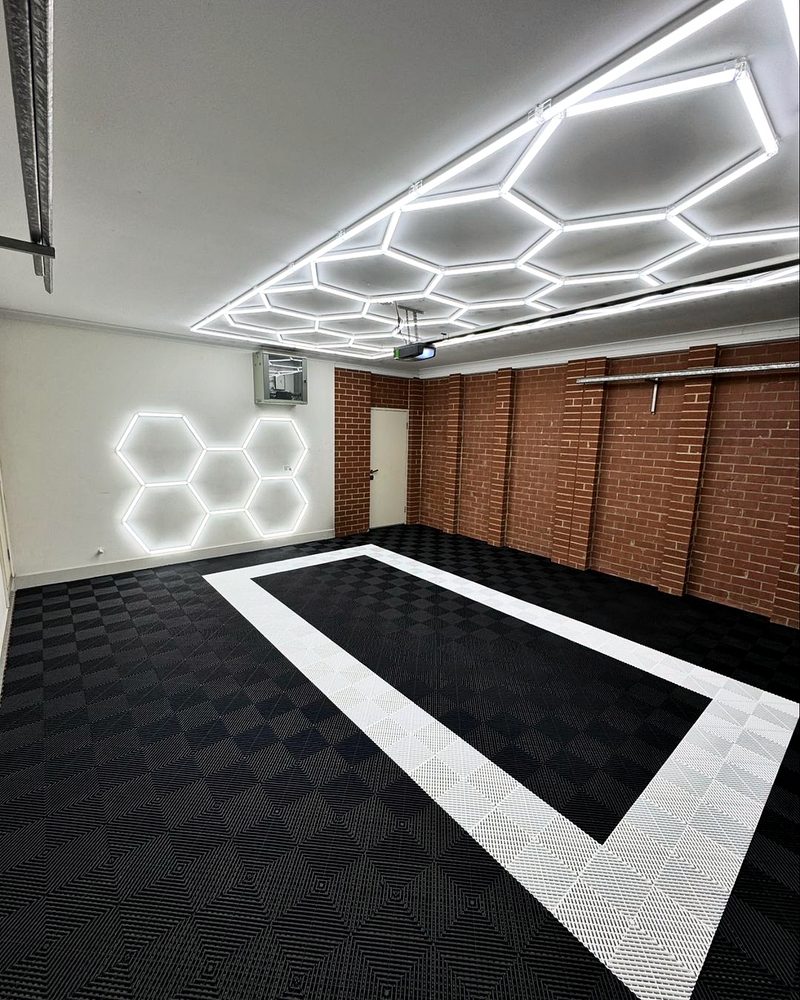ULTRAGRID Jet Black floor with the Alpine White outline, a white wall, a red brick wall and a white door