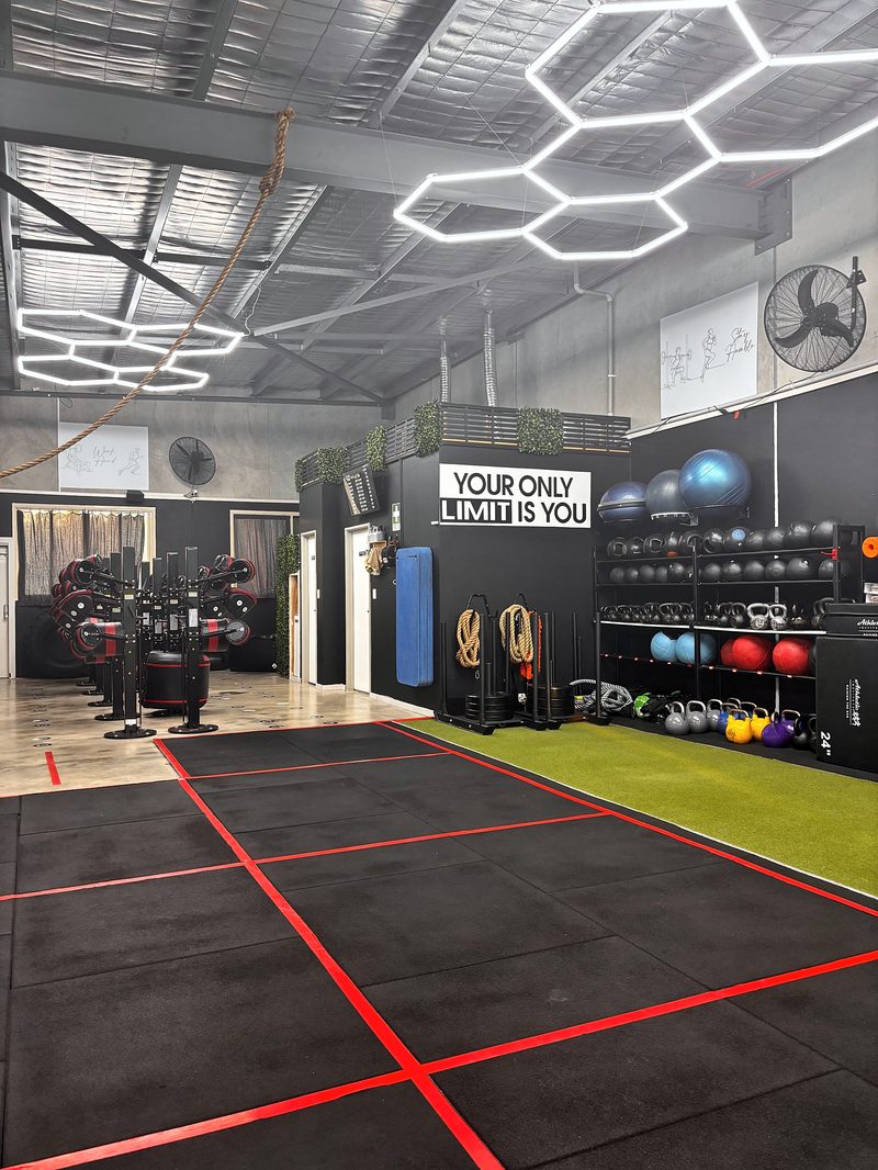 ULTRABEAM hexagon LED lights hung over the Tailored Fitness training floor in Perth, beside the gym's slogan wall and kettlebell racks