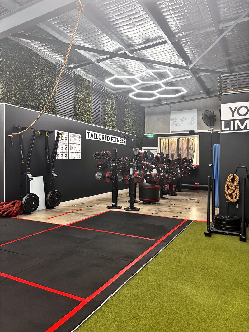 ULTRABEAM hexagon lights over the training floor at Tailored Fitness, with the Tailored Fitness wall sign below