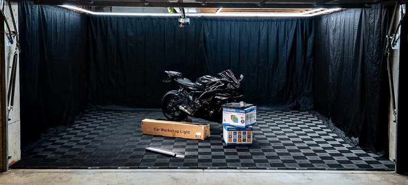 Wide view of the Jet Black ULTRAGRID floor with the bike, an ULTRAGRID carton and a long carton on the floor