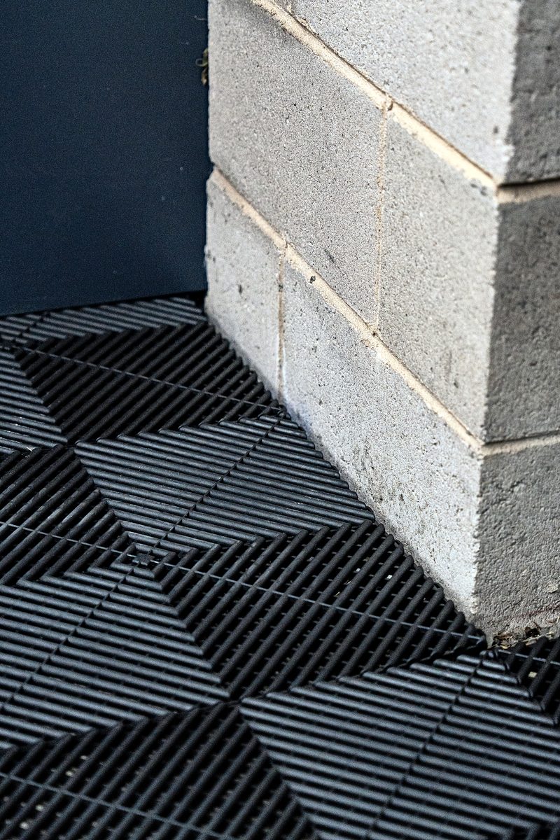 Where the Jet Black ULTRAGRID floor meets a block wall in a corner
