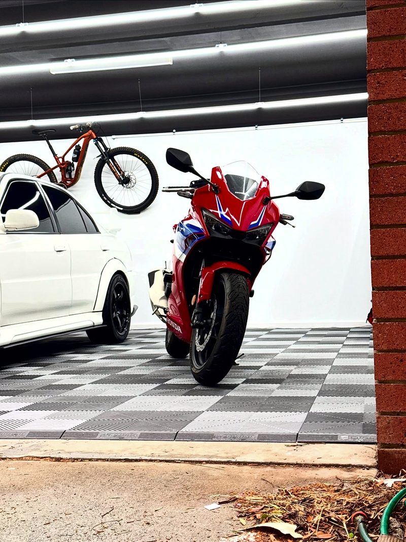 A red Honda CBR parked on the ULTRAGRID Silver Grey and Space Grey chequer, a mountain bike on the white wall behind
