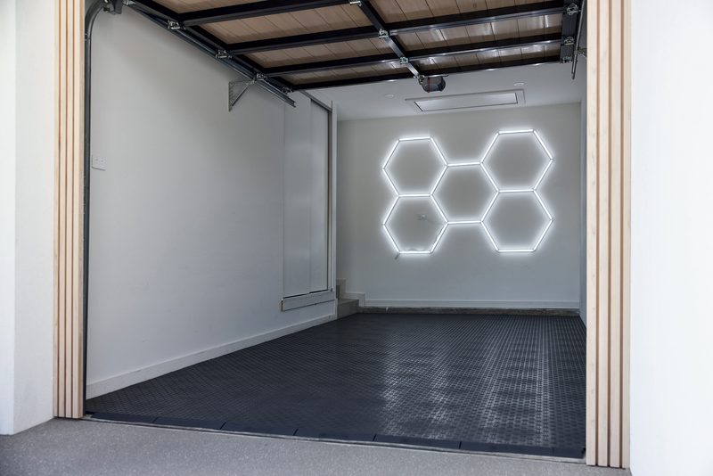 A single garage with a floor of ULTRATUFF Space Grey diamond-tread tiles and a five-hexagon ULTRABEAM light on the white back wall