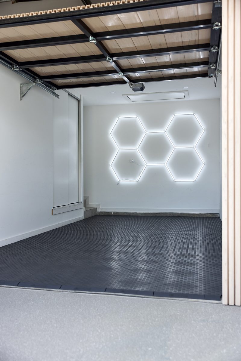 Portrait view of the empty garage: ULTRATUFF Space Grey tiles and the five-hexagon ULTRABEAM light on the back wall