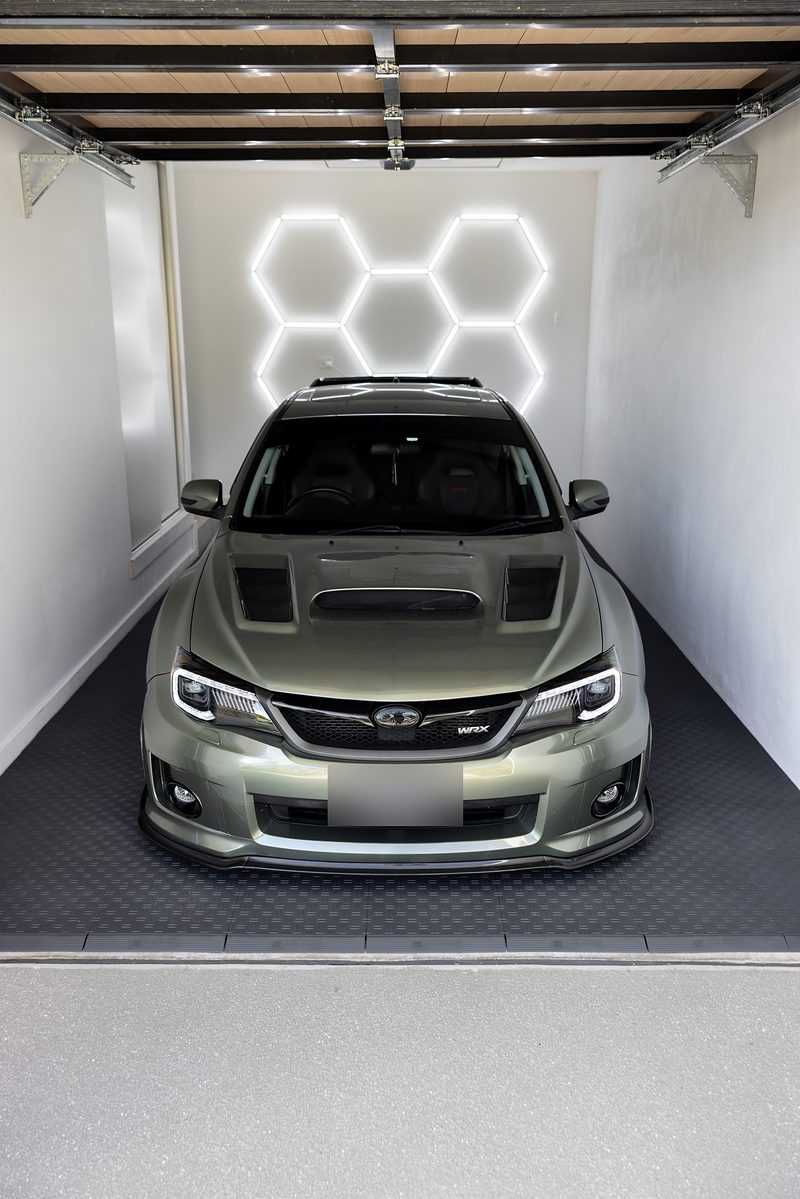 A green Subaru WRX parked head-on on the ULTRATUFF Space Grey floor in front of the hexagon light cluster