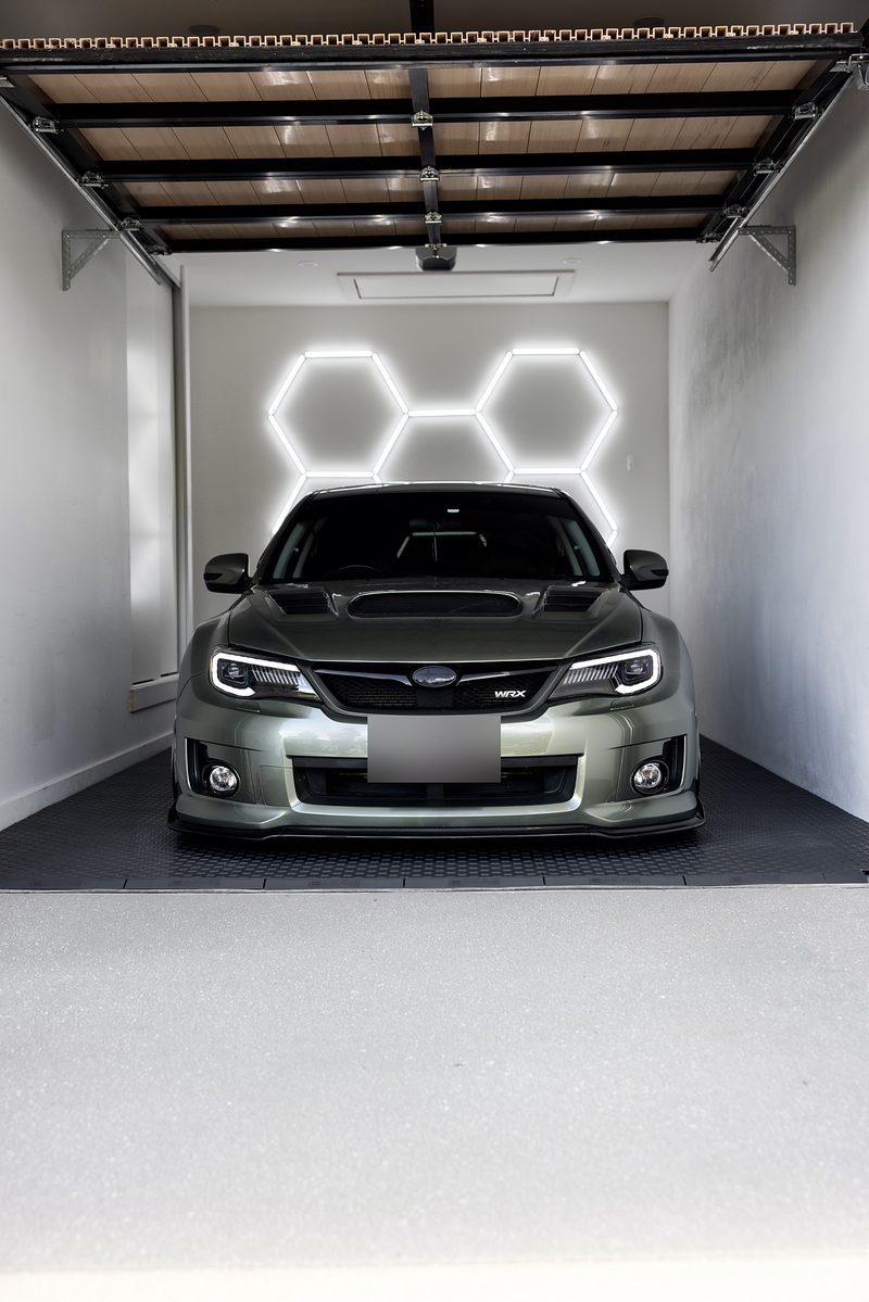 The green Subaru WRX on the ULTRATUFF Space Grey floor, hexagon lights on the wall behind