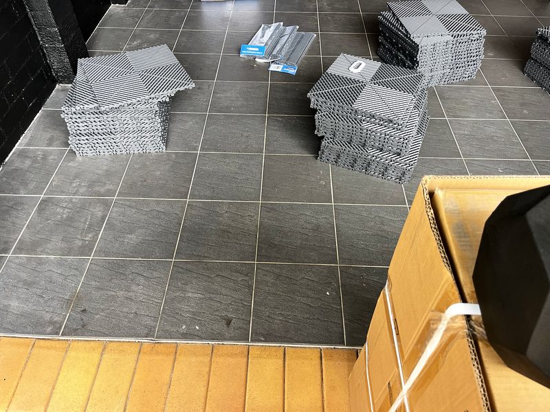 Two stacks of Space Grey ULTRAGRID tiles and a pack of ramps on the old floor