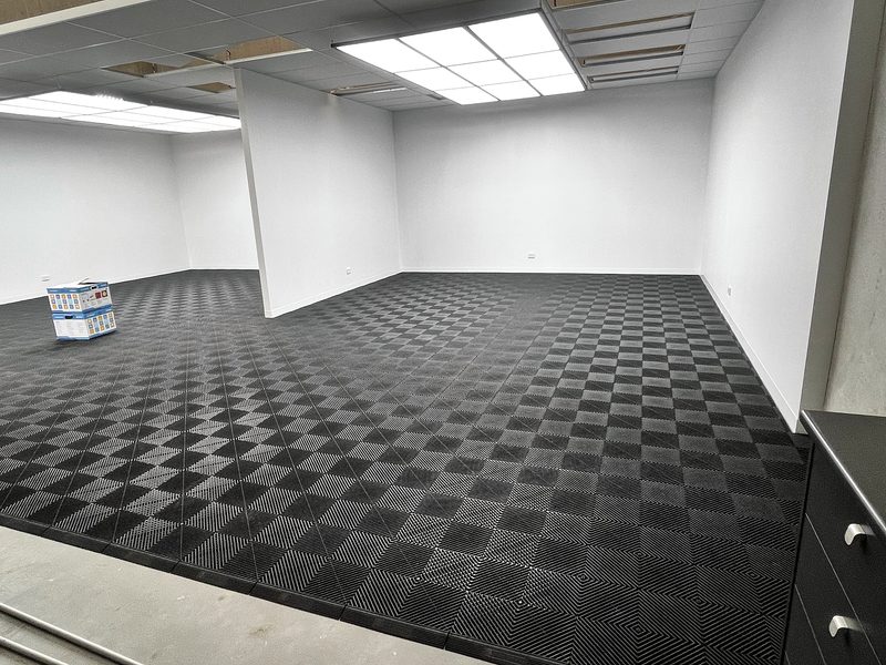 F90 Auto Detailing studio unit in Sydney with a Jet Black ULTRAGRID floor and ULTRAEDGE ramp edge, white walls and a black cabinet