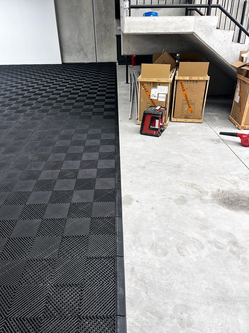 Jet Black ULTRAEDGE ramps finishing the ULTRAGRID floor beside the bare concrete slab