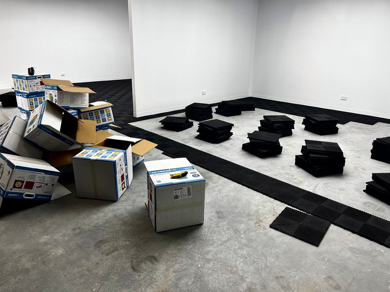 Stacks of Jet Black ULTRAGRID tiles on the bare slab beside the black edge row