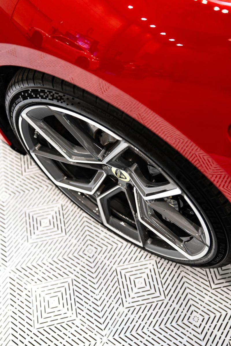 Close view of ULTRACORE Alpine White tiles beside the wheel of a Lotus Emeya